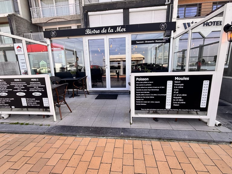 Exterior storefront of Bistro de la Mer restaurant with large windows, menu boards, and brick paving in front